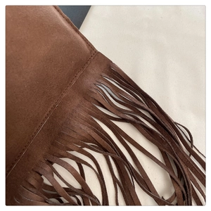 Macro shot of dark brown suede crossbody bag showing fine stitching and fringe detail