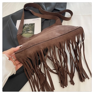 Detail of dark brown suede shoulder bag with bohemian long fringe and retro texture