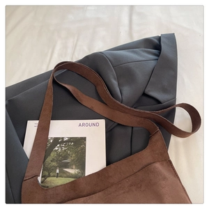 Detail of dark brown matte suede shoulder bag with reinforced stitching and wide strap