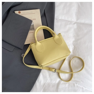 Gros plan d'un sac à main jaune grainé avec bandoulière sur une veste grise