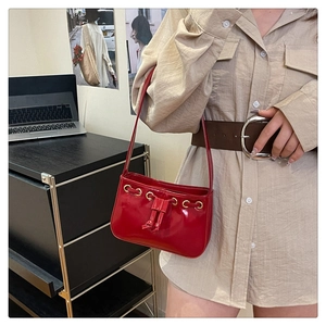 Detail of red patent leather shoulder bag with gold eyelets and drawstring accents