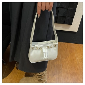 Close-up of white PU leather handbag with gold eyelets and drawstring closure details