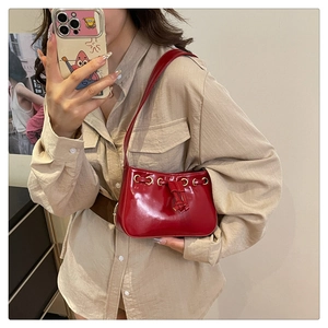 Detail of red patent leather handbag with gold metal ring and drawstring closure