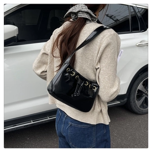 Detail of black minimalist hobo bag with gold metal eyelets and drawstring decor