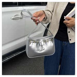Detail of silver metallic shoulder bag featuring drawstring design and gold eyelets