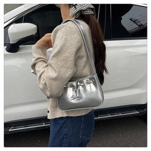 Detail of silver metallic shoulder bag with drawstring closure and golden eyelets