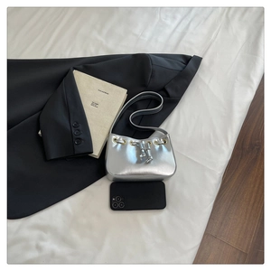 Detail of silver metallic mini bag with drawstring and phone for size comparison