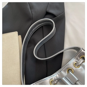 Detail of silver metallic handbag featuring metal eyelet accents and slim shoulder straps