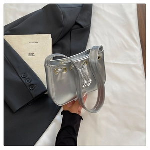 Detailed shot of silver metallic baguette bag with drawstring decor and metal eyelets