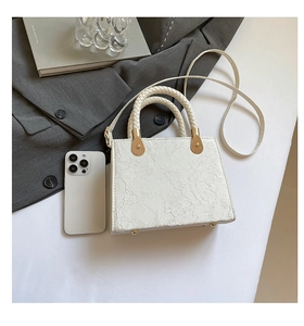 Détail du sac à main blanc gaufré floral avec poignée tressée et clous dorés