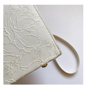 Vue macro détaillée du tissu jacquard blanc à motifs de roses et du clou en métal doré