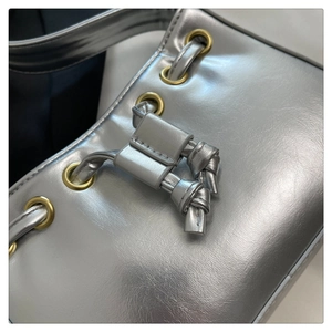 Detail of silver metallic PU bag with golden grommets and knotted strap decoration