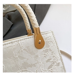 Détail de la texture florale en dentelle blanche et de la poignée tressée avec boucle dorée