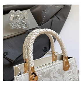 Détail du sac à main blanc crème avec dentelle florale et poignée ronde tissée