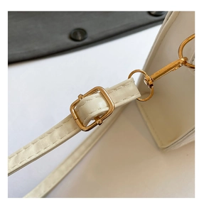 Détail de la bandoulière en cuir blanc avec des boucles en métal doré de haute qualité
