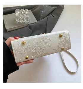 Détail du fond d'un sac en jacquard blanc avec quatre pieds de protection dorés