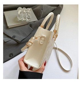 Détail du sac en similicuir crème avec relief floral et poignées tressées élégantes