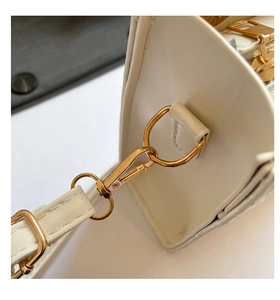 Gros plan des garnitures en métal doré clair et des coutures d'un sac à main blanc crème