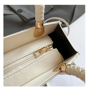 Détail du sac à main en cuir tressé montrant la fermeture éclair dorée et l'intérieur