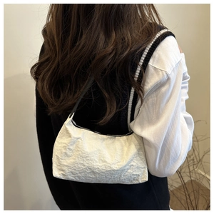 Gros plan sur le sac à bandoulière en nylon blanc plissé avec une fine lanière noire