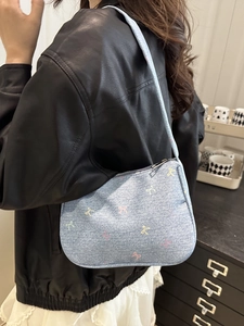 Blue denim shoulder bag with colorful bow prints and minimalist crescent half-moon design