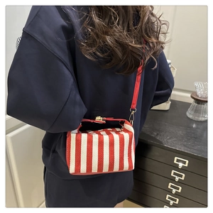 Detail of red and white striped canvas crossbody bag with golden metal buckle and red strap