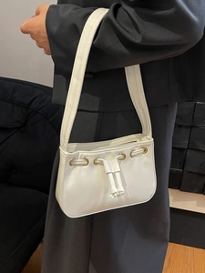 Minimalist white square shoulder bag with drawstring detail and gold accents on a model