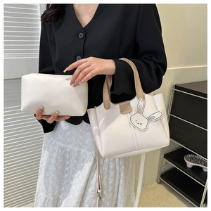 Close-up of white tote bag and matching pouch with cute rabbit charm and fashion logo