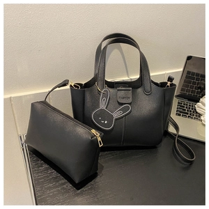 Detail of black tote bag set with FASHION embossing and a cute rabbit charm accessory