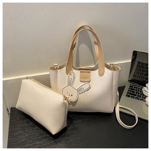 Detail view of cream white PU leather tote set with cute bunny tag on wooden desk