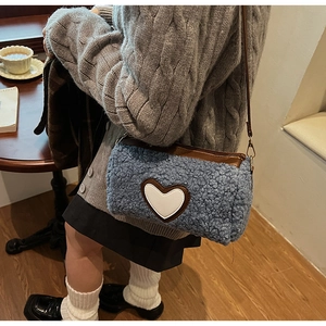 Vue détaillée du sac cylindrique en polaire bleue avec écusson cœur et cuir brun