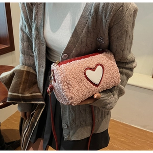 Close-up of plush pink teddy handbag with red heart embroidery and faux leather strap