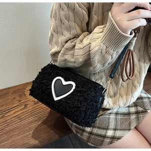 Detail of a plush black heart handbag with faux fur texture and leather strap accents