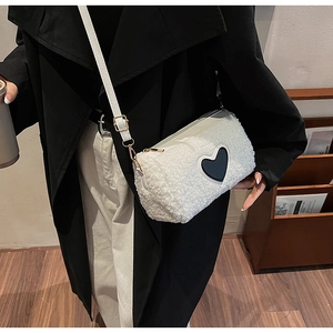 Detail of white plush Boston bag with black leather heart and golden metal hardware