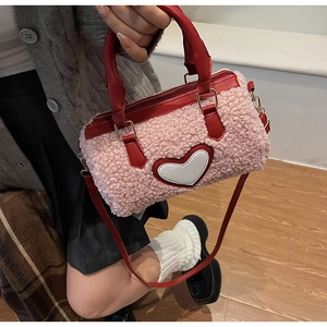 Sac cylindre en peluche rose avec patch cœur blanc et anses en cuir rouge et sangle