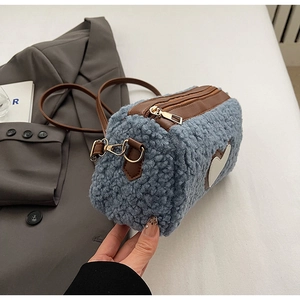 Detail of blue purple plush crossbody bag with heart patch and gold metal hardware