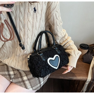 Détail d'un sac à main en peluche noire avec motif de cœur et boucles dorées chic