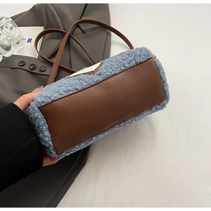 Close-up of blue plush cylindrical handbag with brown leather trim and shoulder strap