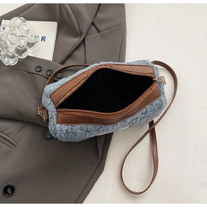 Close-up of the plush blue fabric texture and brown leather strap on the shoulder bag