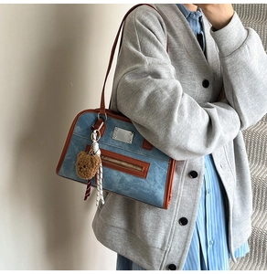 Détail du sac fourre-tout bleu avec bordure en cuir marron et charmant pendentif ours
