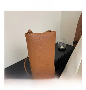 Close-up of brown lychee texture leather bucket bag with embossed logo detail