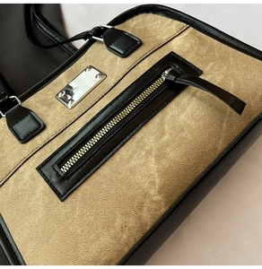 Nahaufnahme der Khaki-Retro-Tasche mit schwarzem Lederbesatz und Silberplakette