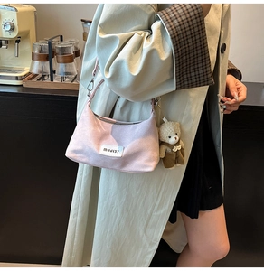 Detail of pink suede dumpling bag with MJJI37 patch and a cute brown plush bear charm