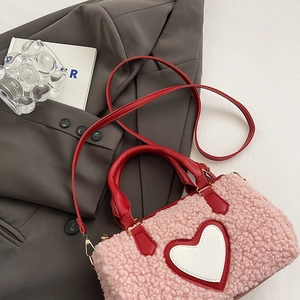 Gros plan sur la texture peluche rose et le motif cœur rouge d'un sac à main