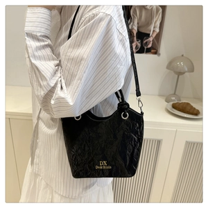 Detailed shot of black pleated leather bucket bag with gold logo and metallic strap ring