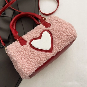 Détail du sac à main rose en peluche avec finitions en cuir rouge et cœur