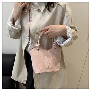Detailed close-up of the textured pale pink leather and adjustable strap on the handbag
