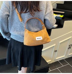 Detail of mustard yellow corduroy dumpling bag with white woven label and top handle