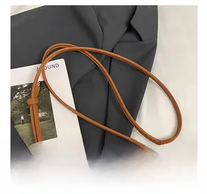 Close-up of adjustable knot on the slim strap of a brown lychee grain leather bucket bag