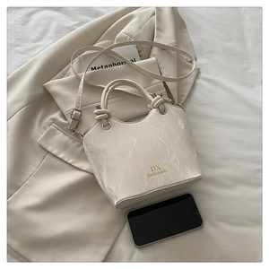 Detailed close-up of marble pattern crossbody bag with golden DX brand lettering and handles